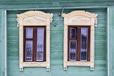 Yeşil bir ahşap evin cephe boyalı. İki windows ışık ile dekoratif ahşap kare oyma sarı. Kar. Rus Halk tarzı. Önden Görünümü Kapat.