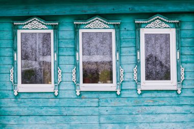 Yeşil bir ahşap evin cephe boyalı. Üç windows beyaz dekoratif Ahşap oyma kare ile. Kar... Rus Halk tarzı. Önden Görünümü Kapat.