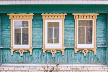Yeşil cephe ahşap bir ev. Üç windows bej dekoratif Ahşap oyma kare ile. Kar. Rus Halk tarzı. Önden Görünümü Kapat.