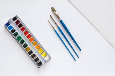 Suluboya, suluboya için üç fırçalar ve beyaz zemin üzerine suluboya kağıdı destesini