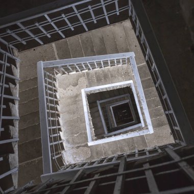 Eski spiral kare beton merdiven ve metal çitler. Üst alt görünüm.