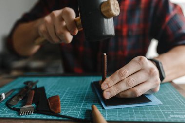 Adam elleri deride çekiçle delikler açıyor.