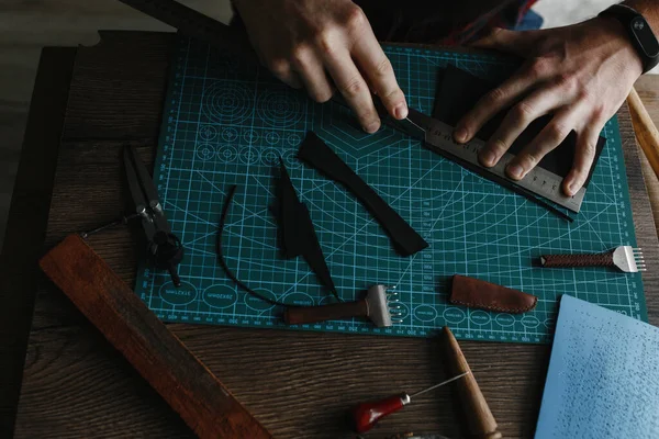 Man hands measuring the leather shred with the ruler