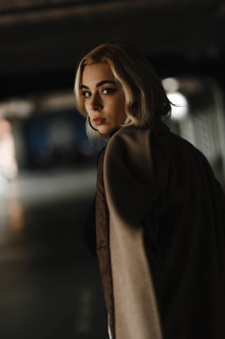 Omzunun üzerinden kameraya bakan genç sarışın kız. Kadın portresi