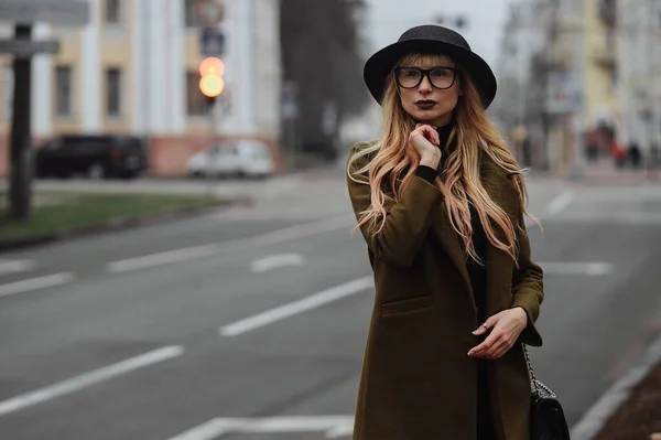 Kobieta w okularach i czarnym kapeluszu stojąca przy drodze i myśląca — Zdjęcie stockowe