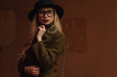 Duvarın arkasında gözlüklü ve şapkalı bir kız.