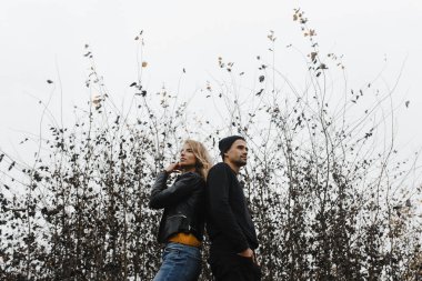 Bir adam ve bir kadın çalıların arkasında sırtı birbirine dönük duruyor. Aşk hikayesi.