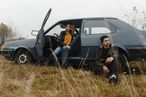 Мужчина и женщина сидят возле машины и думают. История любви
