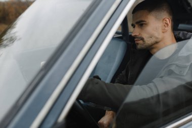 Arabayı süren konsantre olmuş esmer adam. Erkek portresi