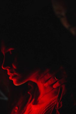 Yakından bir kadın, erkek eli boynunda, neon ışıkta. Aşk hikayesi.