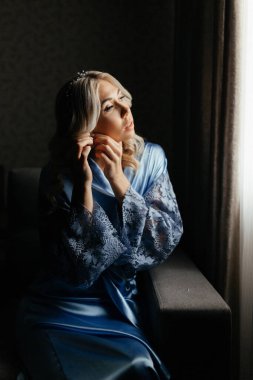 Mavi peignoir takan, küpeli kadın.