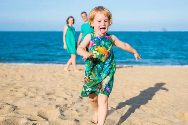 Дочка 4-річна тікає від батьків на пляжі. Сім'я — стокове фото