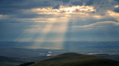 in the mountains, the sun's rays make their way through the clouds in summer