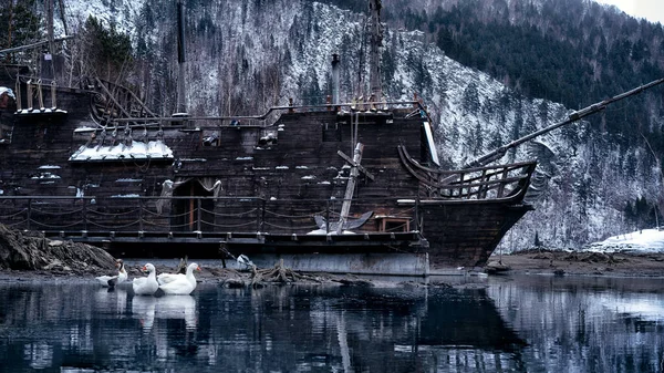 Old Big ship with anchor floating white swans reflection on the water