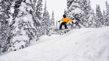 Bir snowboardcu uçar, trambolinde kar treninde zıplar.