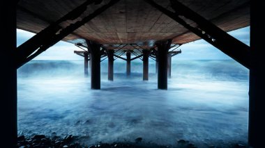 Denizden gelen dalgalar köprünün altındaki ışıklarda