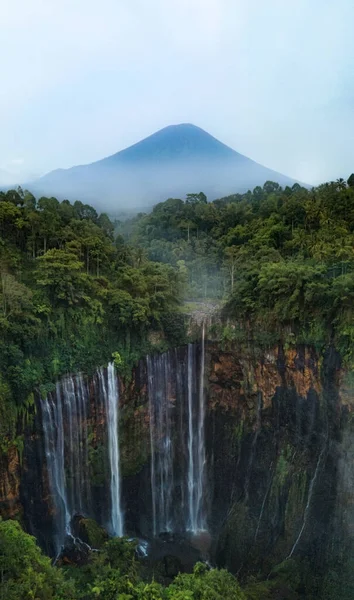 Waterfall Tampak Sowing with a view of the volcano, Indonesia