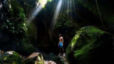 The guy in the canyon the sun's rays beat into the crevice waterfall Tukad Cepung