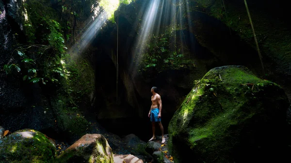 The guy in the canyon the sun's rays beat into the crevice waterfall Tukad Cepung
