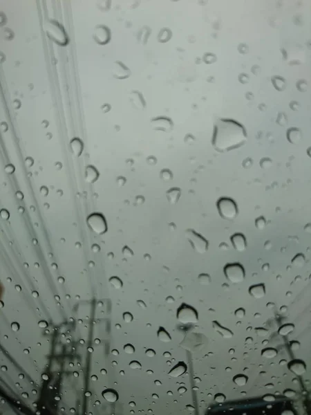 Gotas de chuva no vidro do carro. Vista a partir do interior do carro com um fundo de céu cinza . — Fotografia de Stock