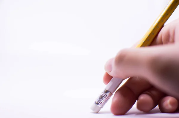 A woman's hand is erasing something with the rubber sticking with the pencil on the white background — Stock Photo, Image
