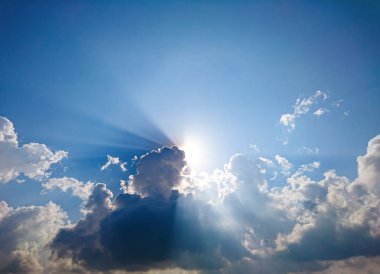White fluffy clouds and sun reflect, in the blue sky