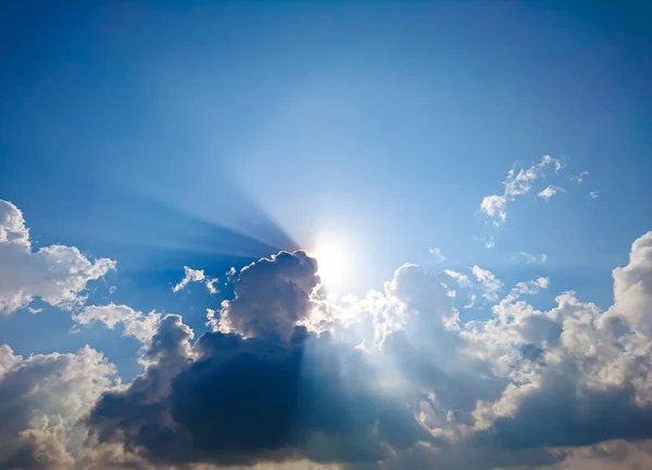 White fluffy clouds and sun reflect, in the blue sky — Stock Photo, Image