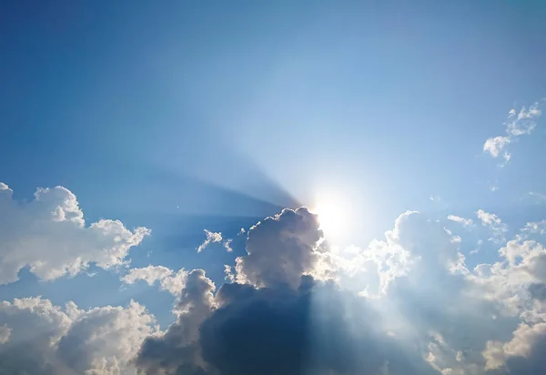 White fluffy clouds and sun reflect, in the blue sky — Stock Photo, Image