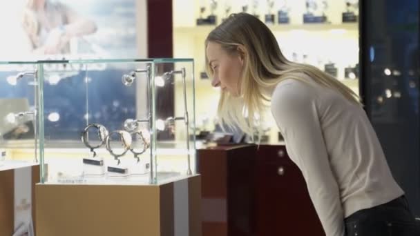 Egy nő órát választ egy modern ékszerboltban. — Stock videók