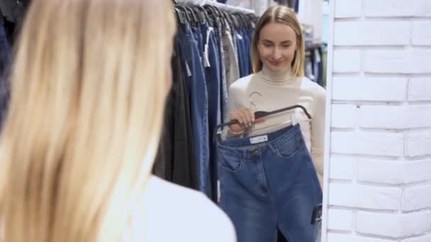 Vrouw in casual kleding kiest voor jeans. In een winkel tijdens een verkoop. — Stockvideo