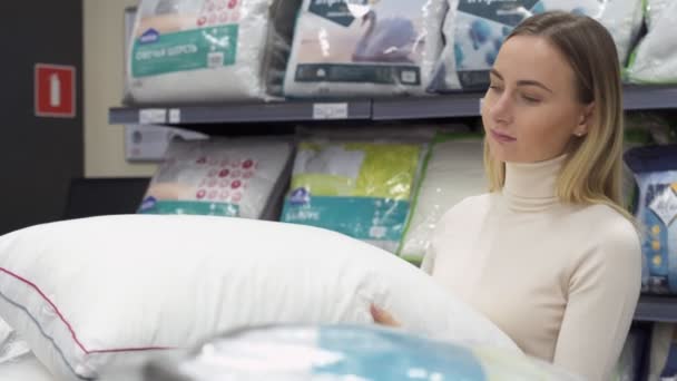 Mujer eligiendo la almohada adecuada para su cama en una moderna tienda de muebles para el hogar — Vídeos de Stock