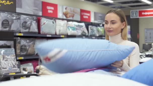 Mujer eligiendo la almohada adecuada para su cama en una moderna tienda de muebles para el hogar — Vídeo de stock