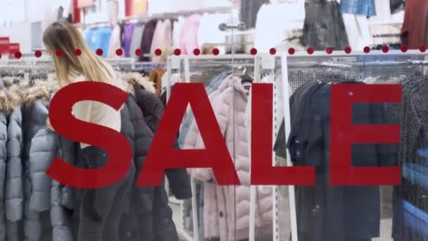 Frau wählt Kleidung im Laden. im Laden große Rabatte — Stockvideo