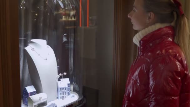 Jeune femme mignonne regarde des bijoux dans la fenêtre du magasin. Client proche de l'exposition de la bijouterie — Video