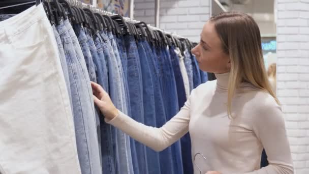 Frau in Freizeitkleidung wählt Jeans. in einem Geschäft während eines Verkaufs. — Stockvideo