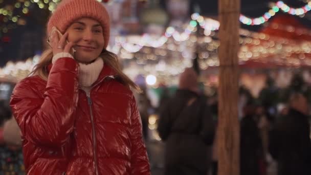 Turista donna che parla sullo smartphone mentre cammina per strada con decorazioni per Natale e distogliendo lo sguardo — Video Stock