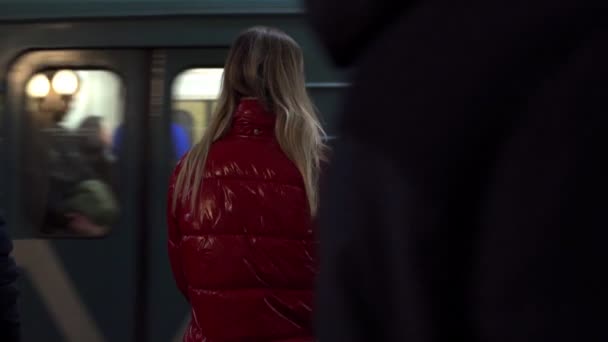 Женщина ждет на платформе, пока поезд метро подъезжает к станции перед ней. — стоковое видео