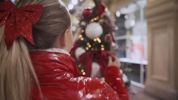 A woman in a red jacket is decorated with a Christmas tree toy — Stock Video