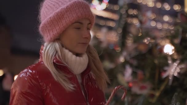 Dziewczyna spaceru w Boże Narodzenie rynku ozdobione lampki świąteczne w godzinach wieczornych. Czuję się szczęśliwy w wielkim mieście. — Wideo stockowe