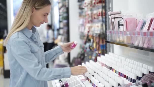 Mujer elige esmalte de uñas en la tienda — Vídeo de stock