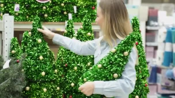 Nő a boltban választ egy mesterséges karácsonyfa, karácsonyi dekoráció. — Stock videók
