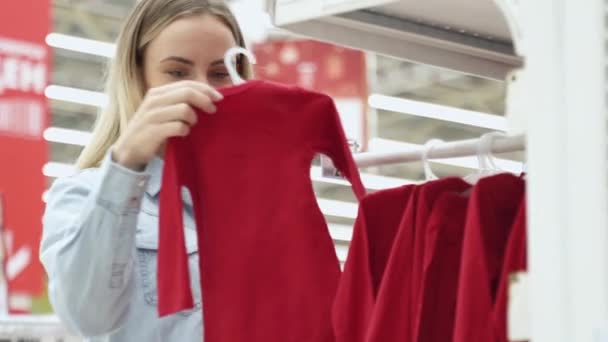Käuferin wählt Kleidung für ihr Kind im Kinderbekleidungsgeschäft — Stockvideo