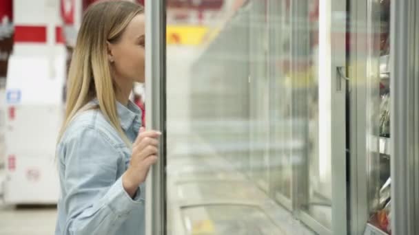 Vrouw winkelen in de supermarkt Het kiezen van bevroren producten in de koelkast — Stockvideo