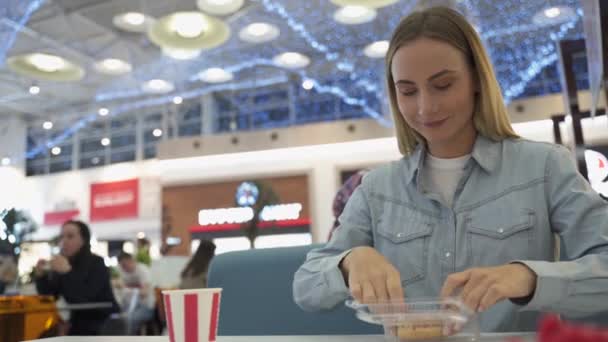 Mujer joven comiendo donut en el centro comercial — Vídeos de Stock