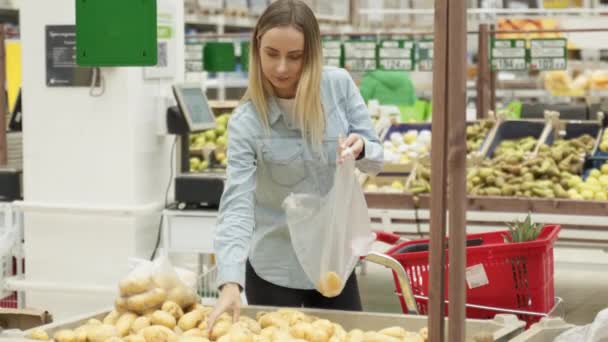 在杂货店挑选土豆的年轻女人笑着 — 图库视频影像