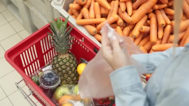 Mulher escolhe cenoura no supermercado . — Vídeo de Stock