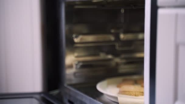 Jonge mooie vrouw trekt peperkoek uit de oven. — Stockvideo