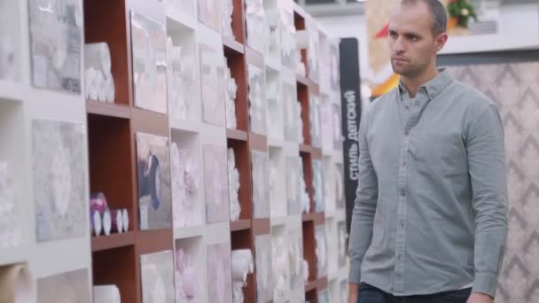 Masculino consumidor compra papéis de parede na loja de ferragens — Vídeo de Stock