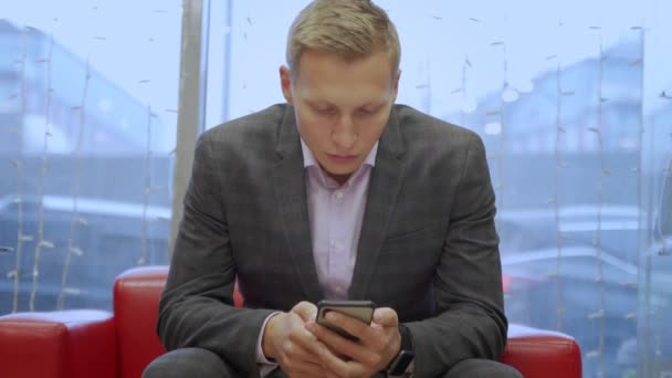 En stilig ung affärsman använder sin telefon — Stockvideo