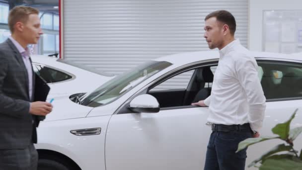 Muž ruka dává klíčky od auta mužské ruce v prodejně aut zblízka. Prodavač aut a muž, který si koupil auto, si potřásli rukou. — Stock video